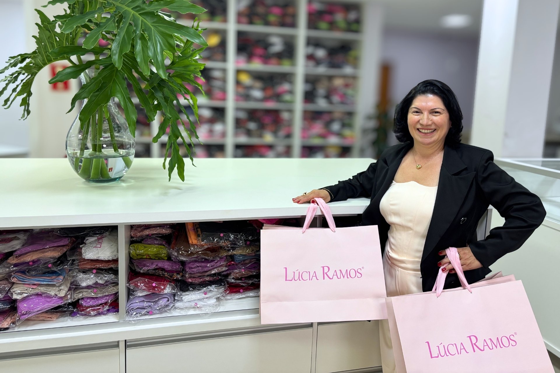 Lúcia Ramos segurando uma sacola de revendedora lingerie no balcão da empresa